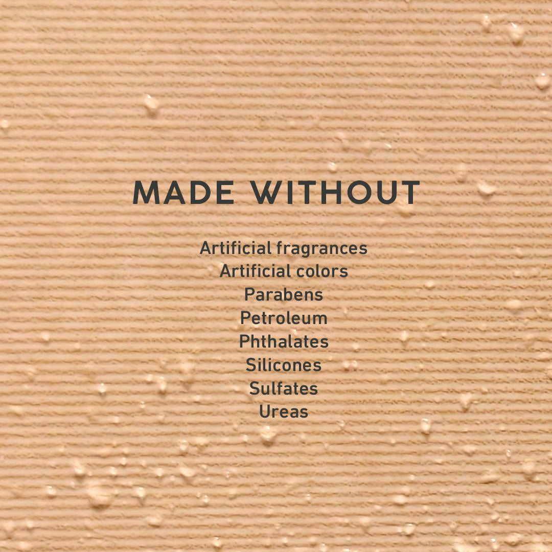 A close-up textured beige surface with the text 'MADE WITHOUT' and a list of ingredients: Artificial fragrances, Artificial colors, Parabens, Petroleum, Phthalates, Silicones, Sulfates, Ureas.