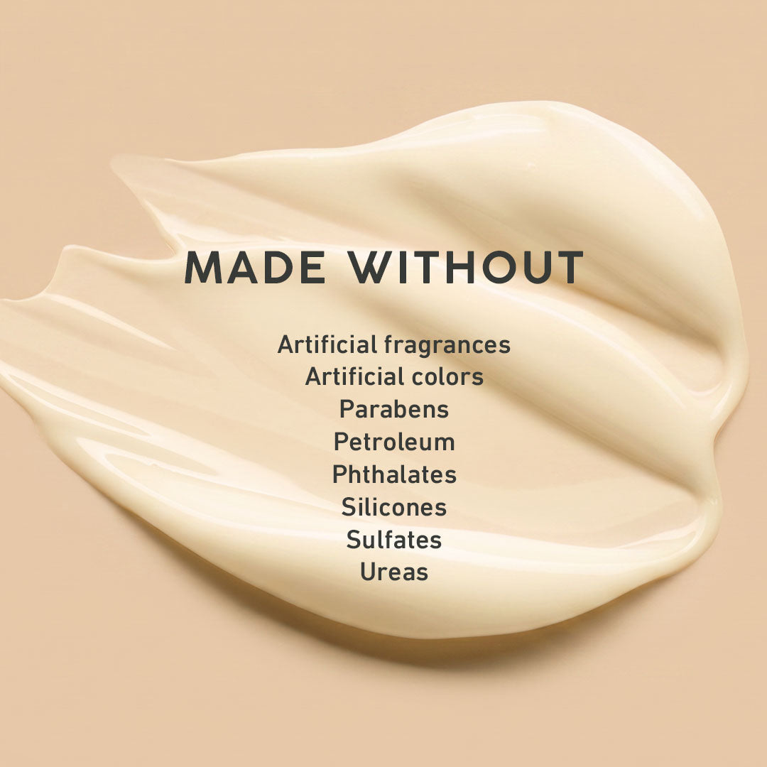 A cream-colored product smear on a warm beige background with the text 'MADE WITHOUT' and a list of excluded ingredients including artificial fragrances, parabens, petroleum, phthalates, silicones, sulfates, and ureas.